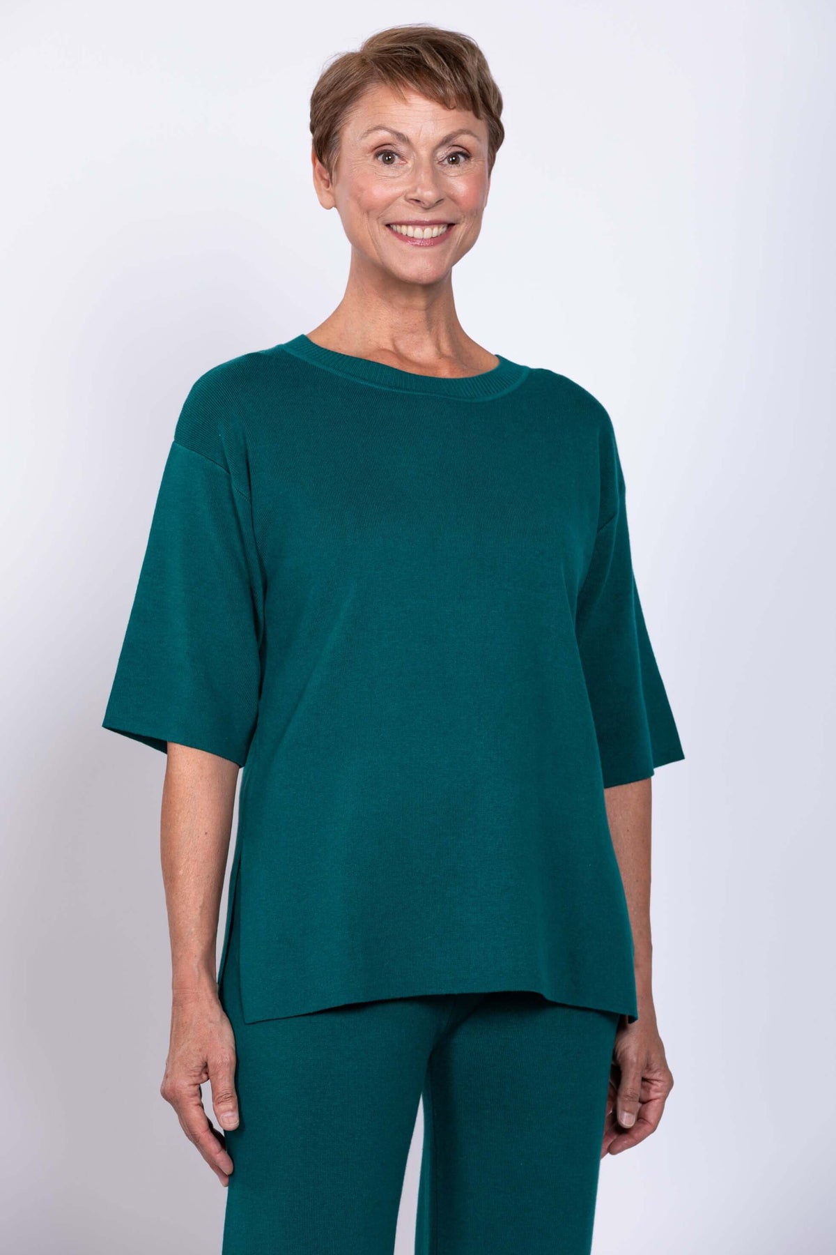 Woman wearing teal short sleeve crew neck sweater with matching pants, front view