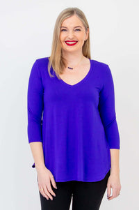 Woman wearing a vibrant purple V-neck 3/4 sleeve top, front view, smiling