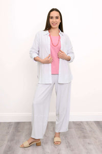 Woman wearing wide-leg white pants with a pink top and white button-up shirt