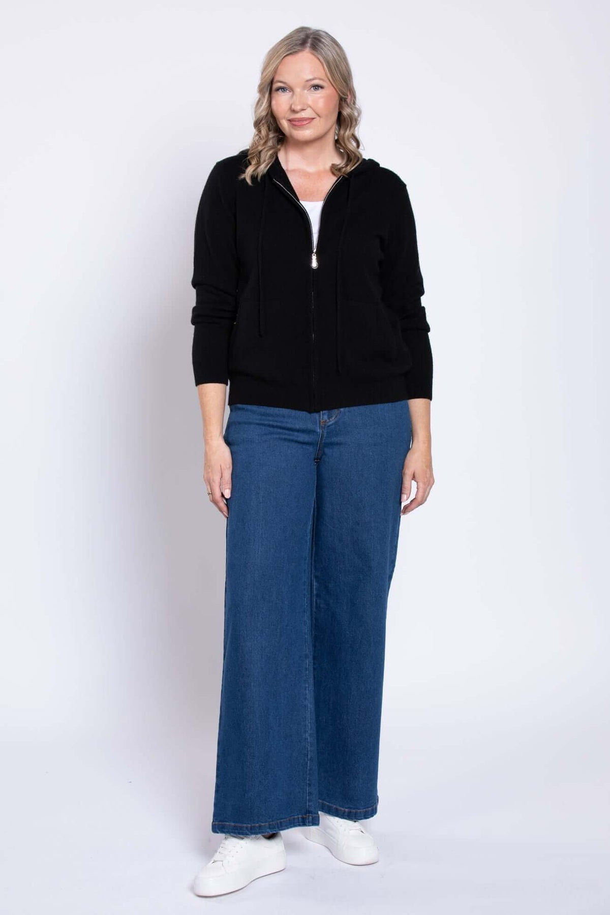 Woman wearing wide leg denim jeans and black hoodie, front view