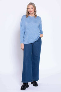 Woman wearing wide leg denim jeans and a light blue top, frontal view