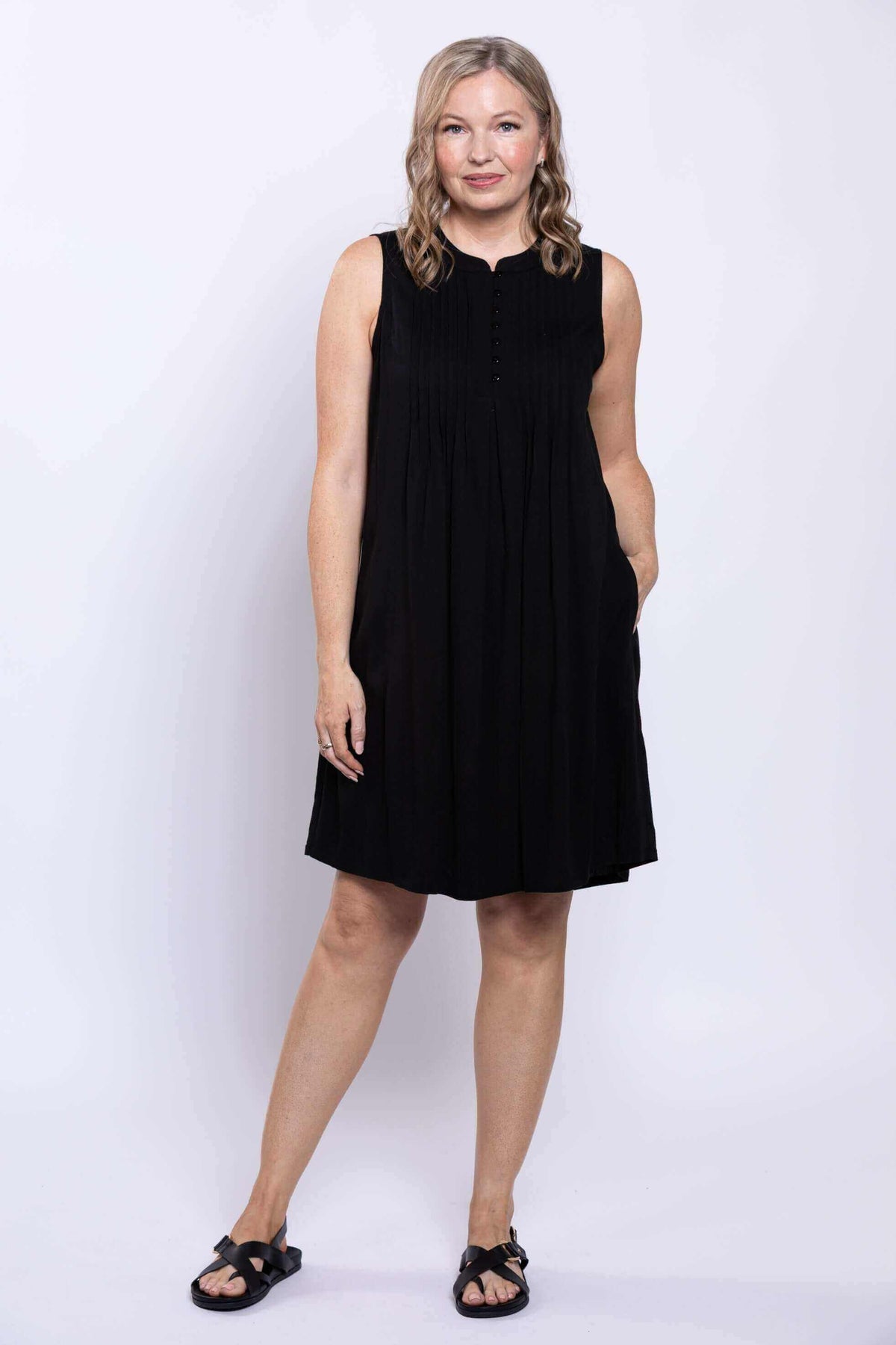 Woman with hand in pocket modeling black sleeveless A-line dress