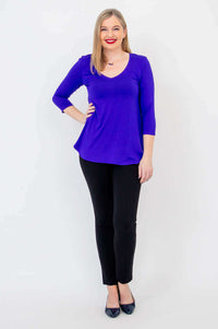 Woman with hand on hip in sapphire blue V-neck bamboo top and black pants