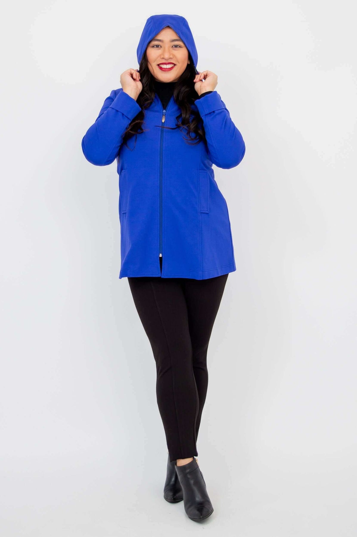 Woman wearing cobalt blue coat with hood up, smiling at the camera