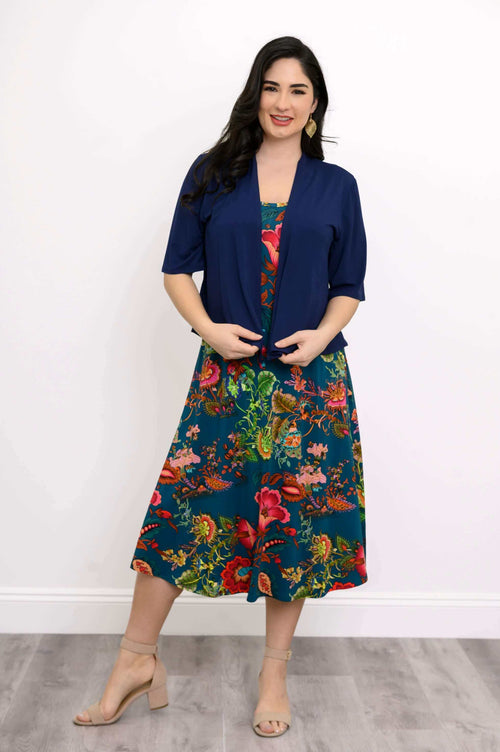 Woman layering a navy cardigan over a teal floral sleeveless midi dress