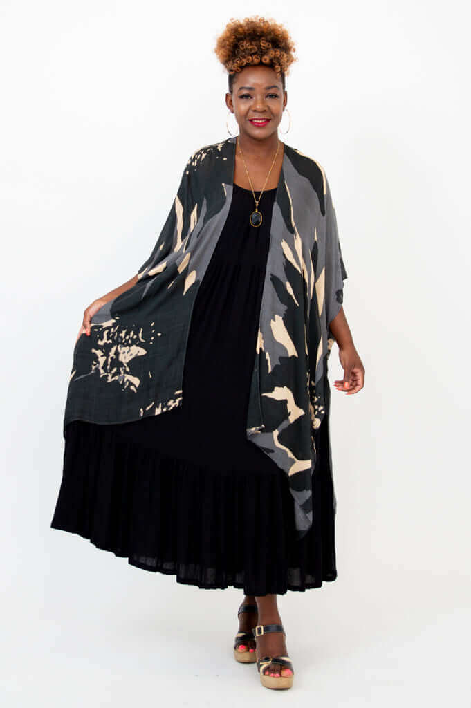 Woman with one arm outstretched wearing Darcy kimono wrap and black dress