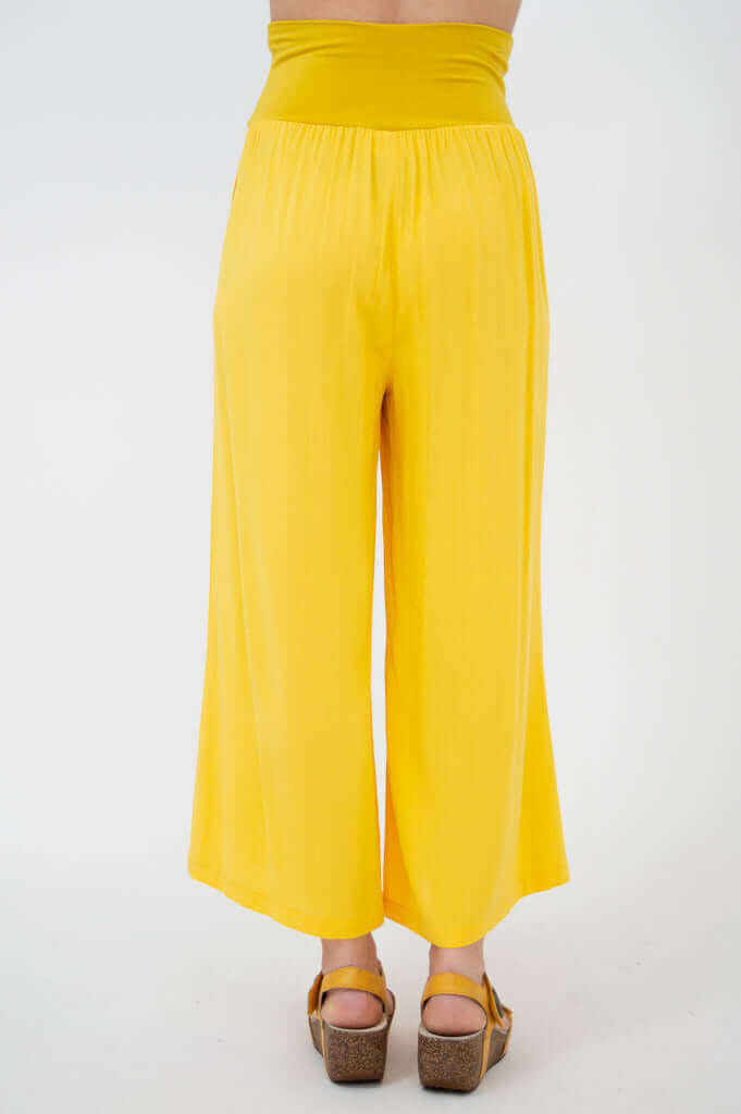 Yellow wide-leg cropped capri pants with deep waistband, rear view closeup